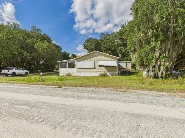 a view of a house with a yard and large trees