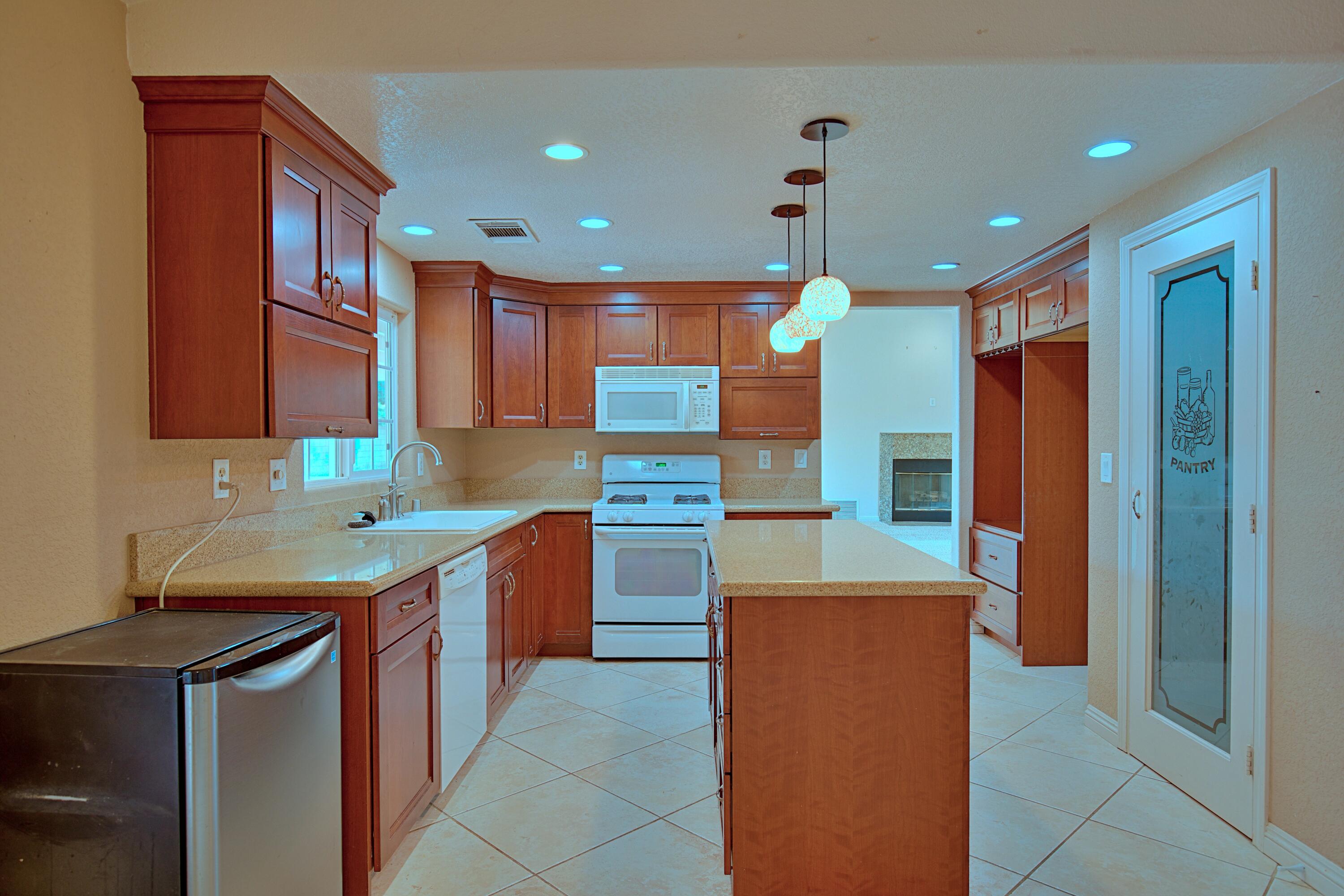 80025 Kingston Drive Bermuda Dunes, CA 92203 - Photo 6 of 27 a kitchen with kitchen island granite countertop a sink and a refrigerator