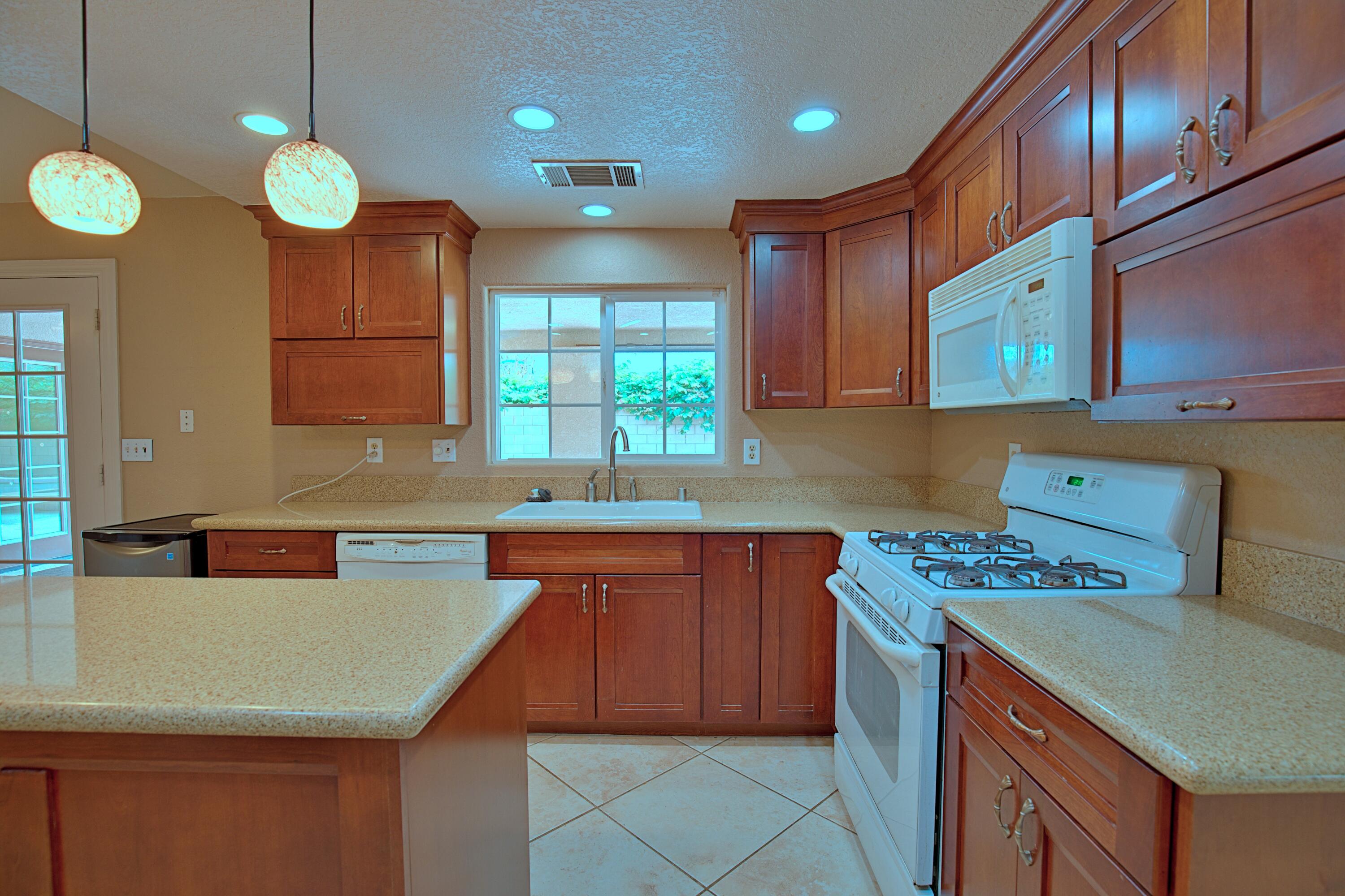 80025 Kingston Drive Bermuda Dunes, CA 92203 - Photo 9 of 27 a kitchen with kitchen island granite countertop a sink cabinets and window