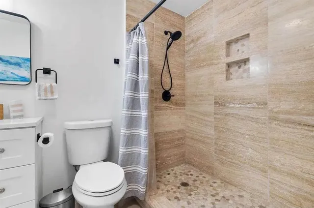 a white toilet sitting next to a bathroom sink and a shower