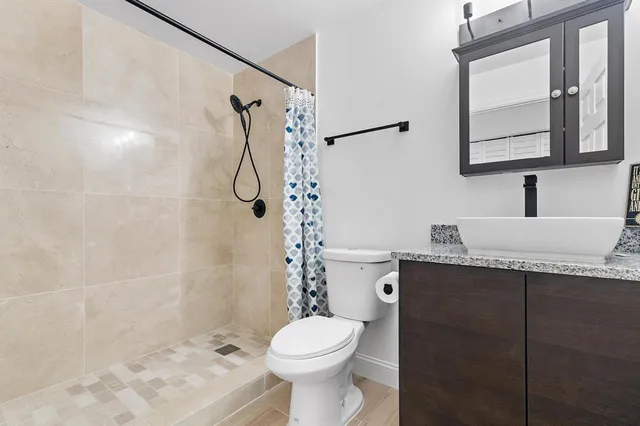 a bathroom with a granite countertop sink toilet and shower