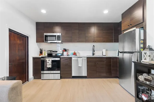 a kitchen with stainless steel appliances kitchen island granite countertop a refrigerator oven a sink and dishwasher