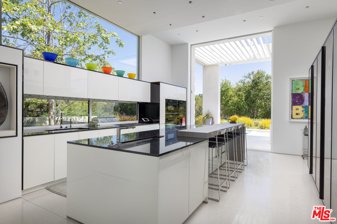 12251 Castlegate Drive Los Angeles, CA 90049 - Photo 11 of 30 a kitchen with stainless steel appliances granite countertop a large window and a dining table