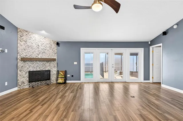 a view of an empty room with wooden floor fireplace and a window