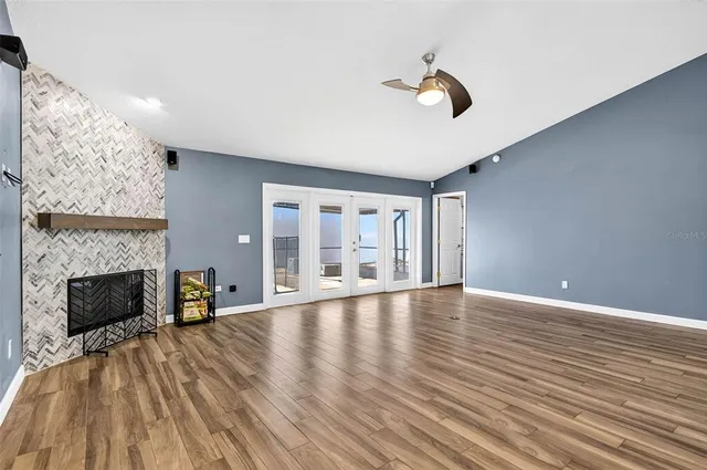 a view of an empty room with wooden floor fireplace and a window