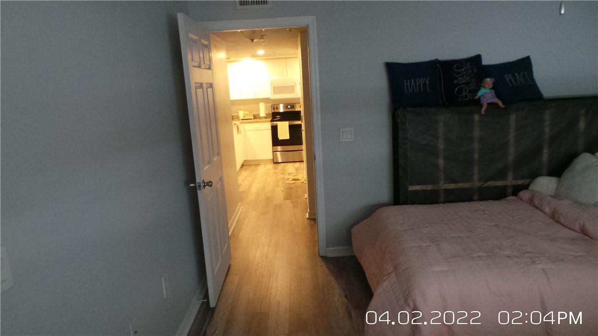 5001 Wiles Road, Unit 106 Pompano Beach, FL 33073 - Photo 13 of 31 a bedroom with a bed and wooden floor