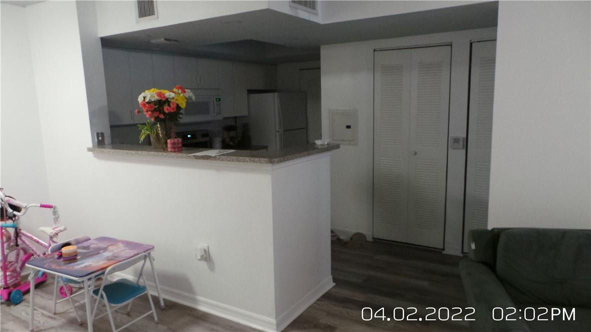 5001 Wiles Road, Unit 106 Pompano Beach, FL 33073 - Photo 8 of 31 a hallway with painting on the wall and a potted plant