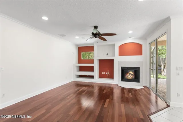 a view of an empty room with wooden floor fireplace and a window
