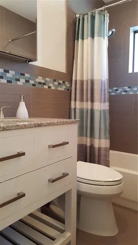 a bathroom with a granite countertop sink toilet and shower