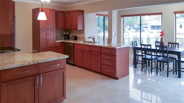 a kitchen with stainless steel appliances granite countertop wooden cabinets a dining table and chairs