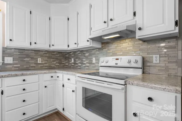 a kitchen with granite countertop white cabinets and a stove