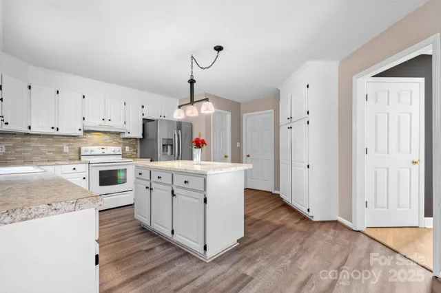 a kitchen with cabinets wooden floor and stainless steel appliances