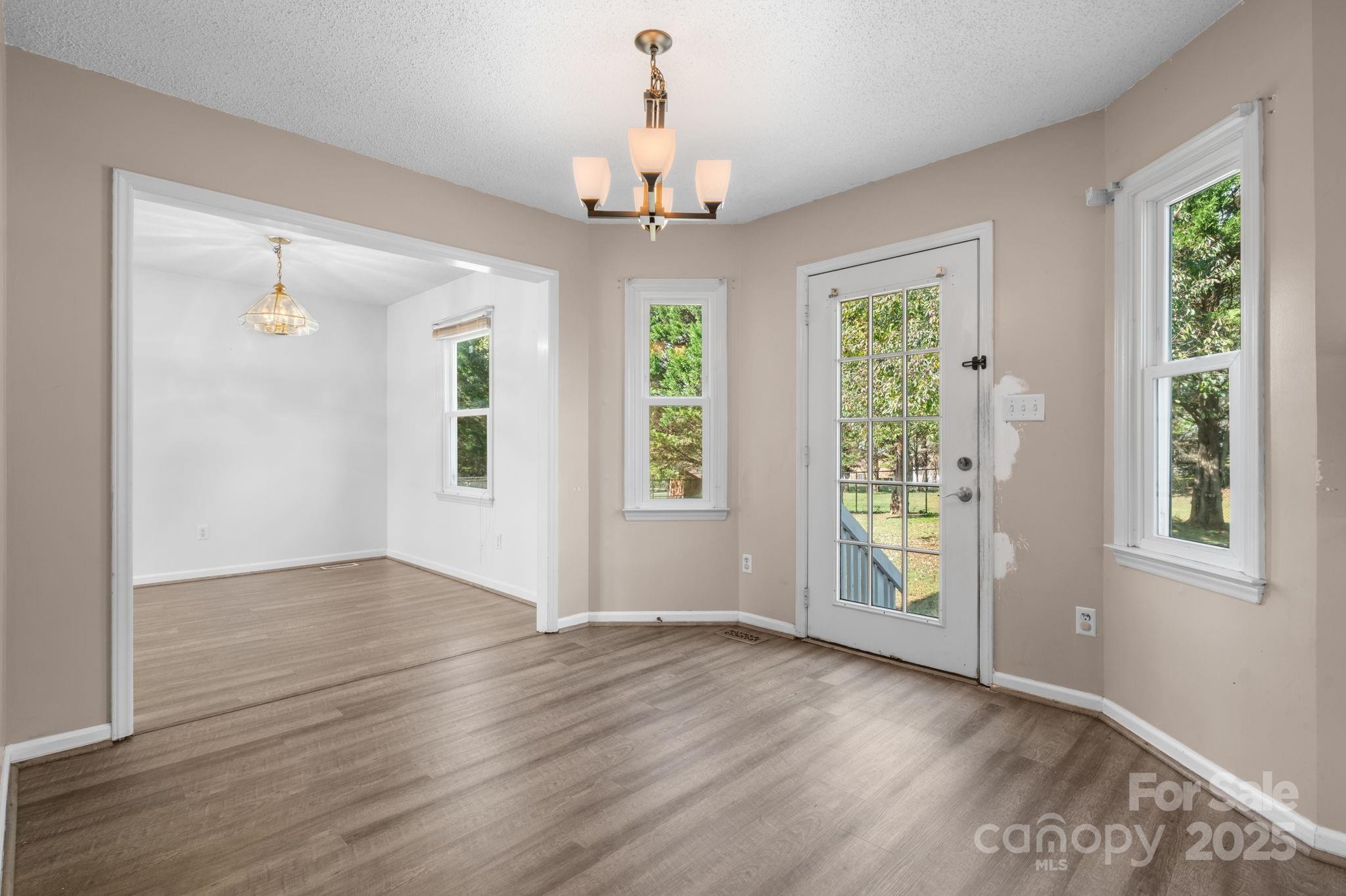 712 Painted Feather Lane Conover, NC 28613 - Photo 8 of 48 an empty room with wooden floor chandelier and windows