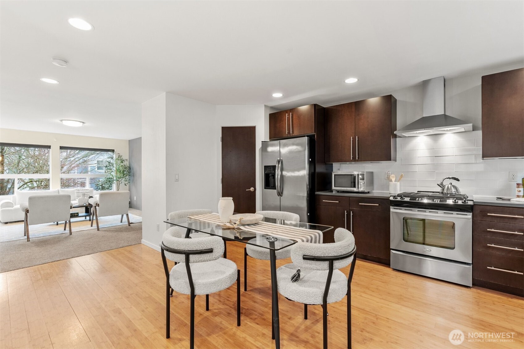 6536 42nd Avenue Southwest, Unit B Seattle, WA 98136 - Photo 11 of 27 a kitchen with stainless steel appliances kitchen island granite countertop a stove a refrigerator a sink a dining table and chairs with wooden floor