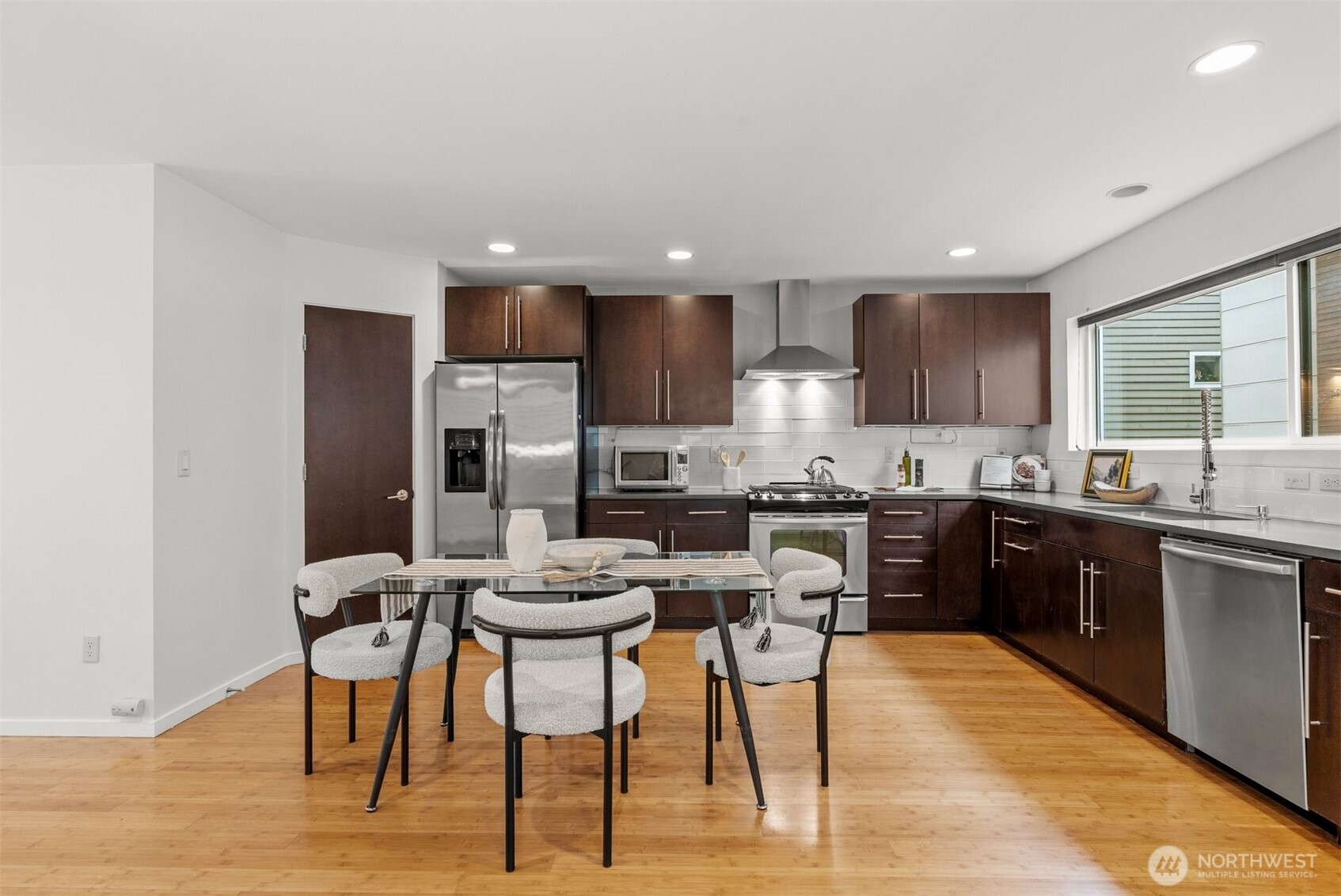 6536 42nd Avenue Southwest, Unit B Seattle, WA 98136 - Photo 8 of 27 a kitchen with stainless steel appliances kitchen island granite countertop a table chairs sink refrigerator and cabinets