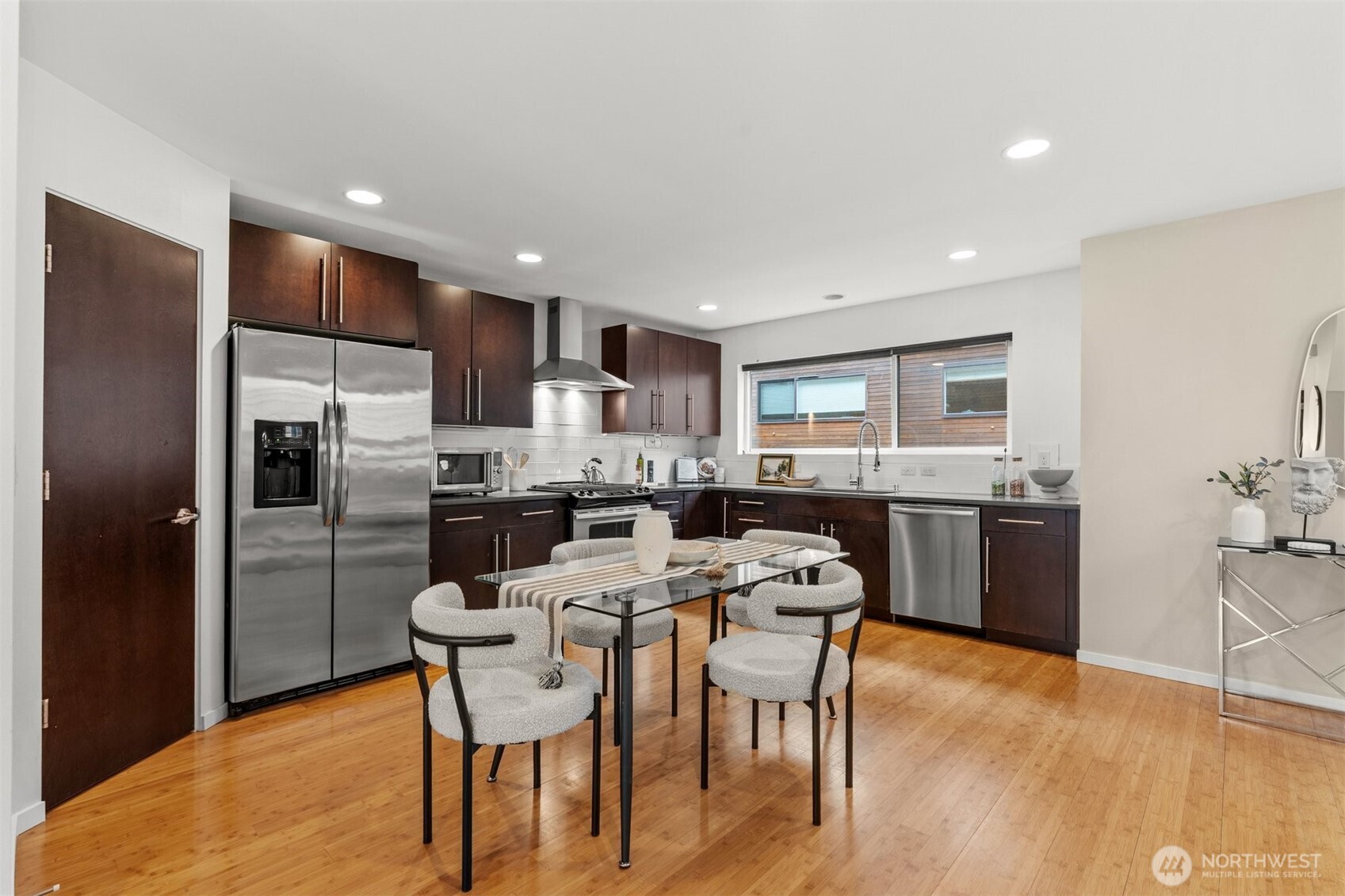6536 42nd Avenue Southwest, Unit B Seattle, WA 98136 - Photo 10 of 27 a kitchen with stainless steel appliances a dining table chairs refrigerator sink and cabinets