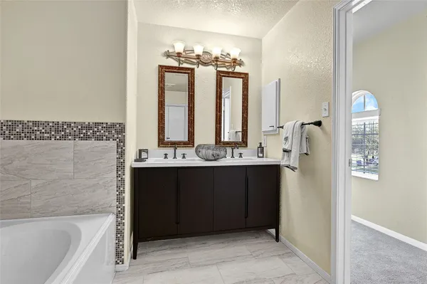 a bathroom with a bathtub sink vanity and mirror