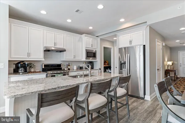 a kitchen with stainless steel appliances granite countertop a table chairs sink refrigerator and cabinets