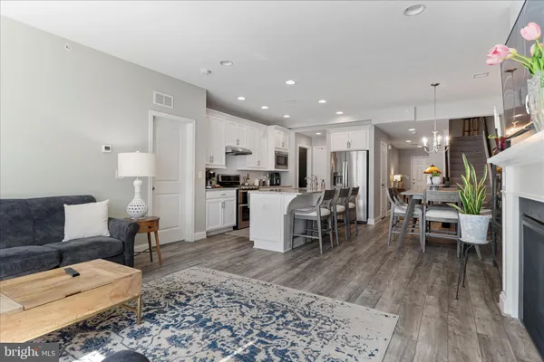 a living room with furniture and kitchen view with wooden floor