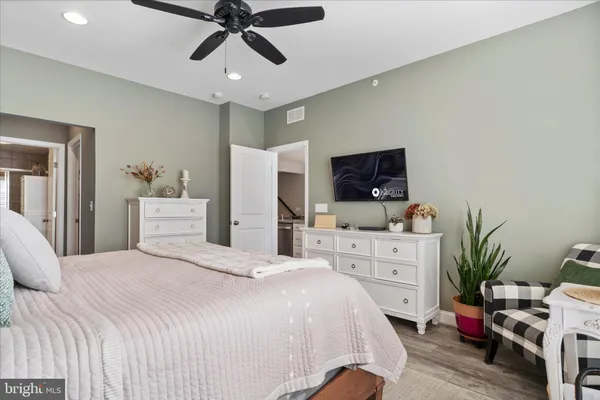 a bedroom with a bed potted plant on dresser and a flat screen tv