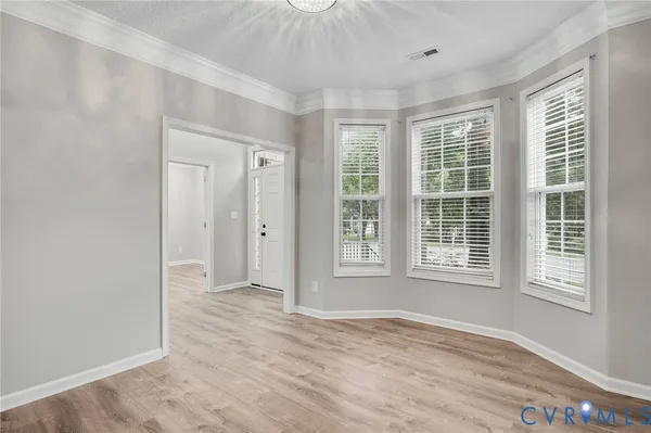 an empty room with wooden floor and windows