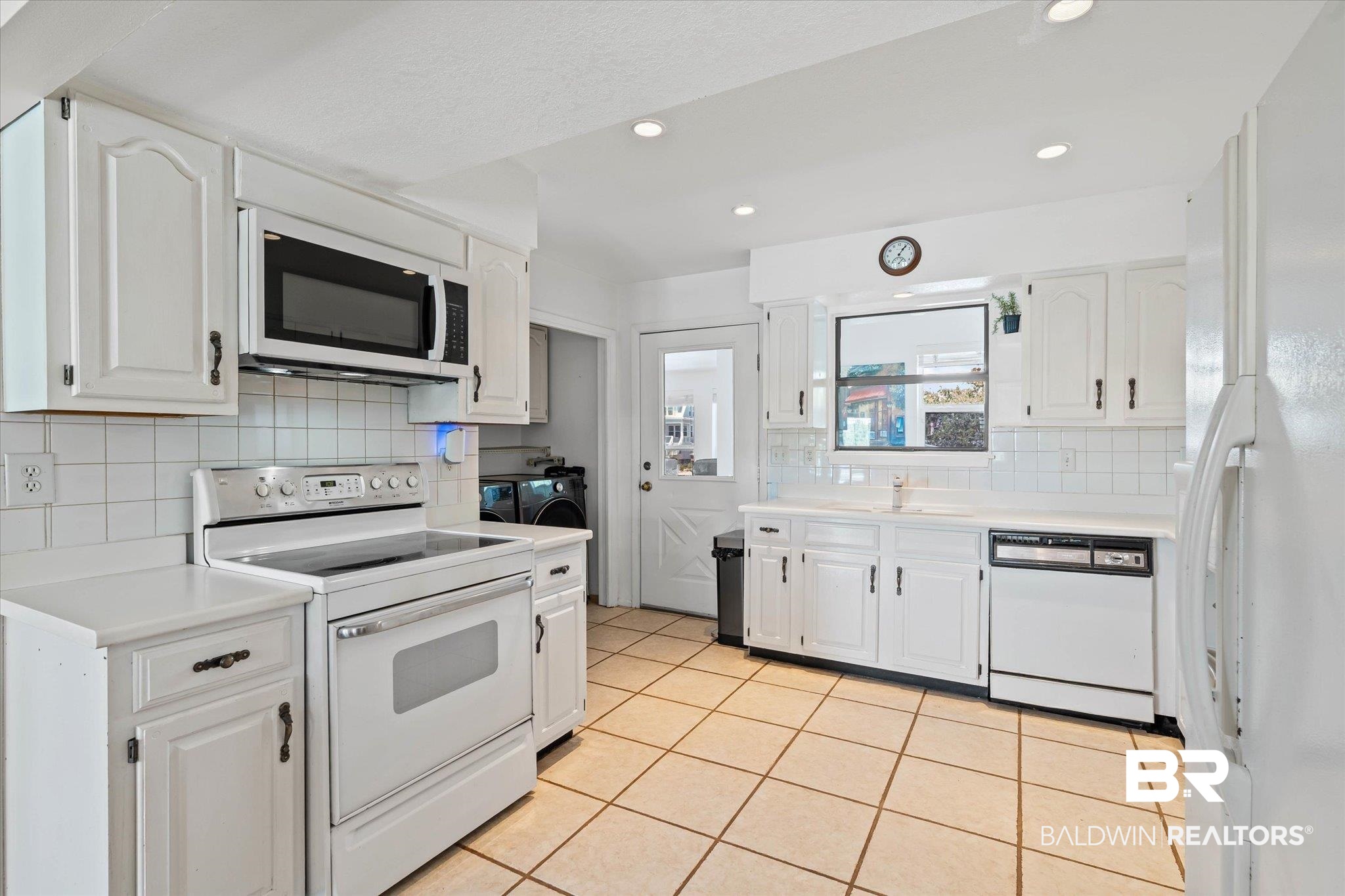 Kitchen featuring white appliances, light countertops, white cabinets, and recessed lighting