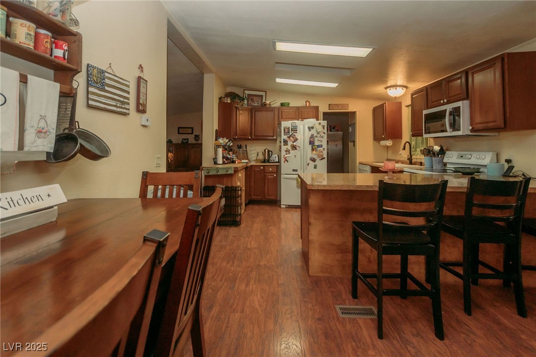3485 Gally Road Pahrump, NV 89060 - Photo 59 of 90 Kitchen with white appliances, dark wood-style flooring, a peninsula, a kitchen bar, and light countertops