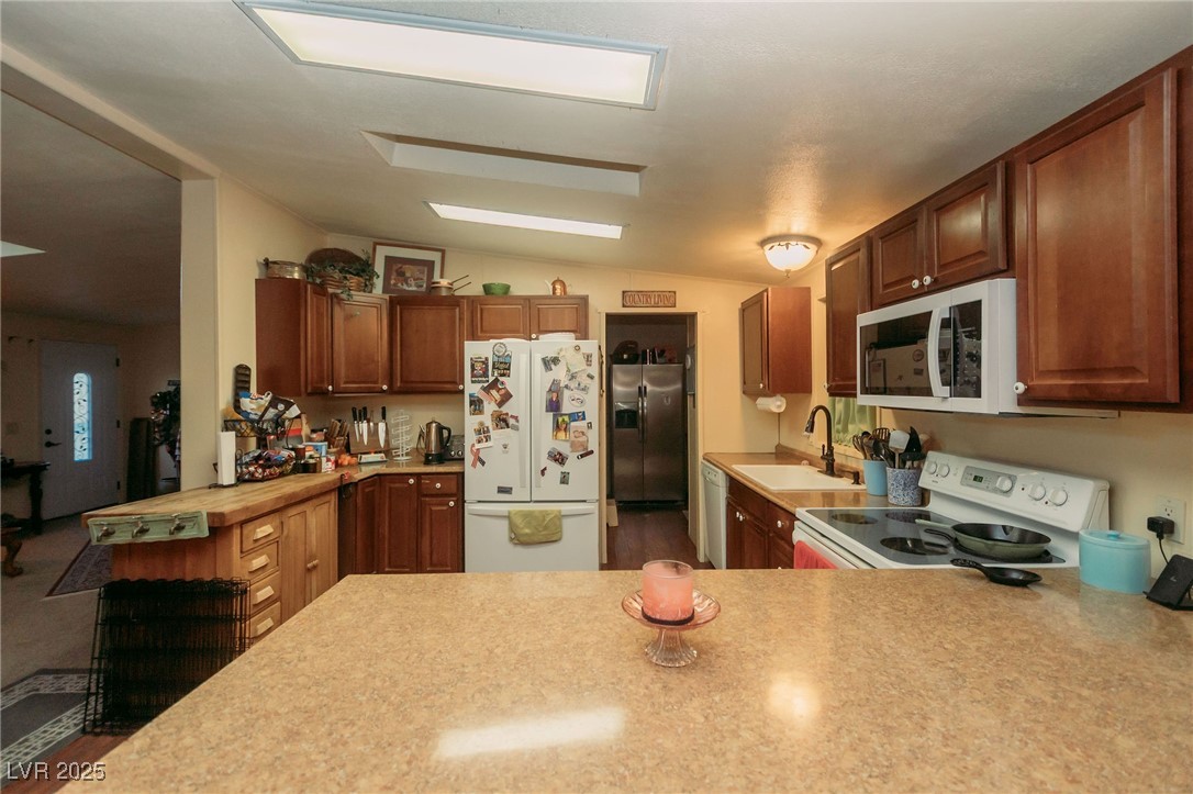 3485 Gally Road Pahrump, NV 89060 - Photo 60 of 90 Kitchen featuring white appliances, light countertops, vaulted ceiling, and a peninsula