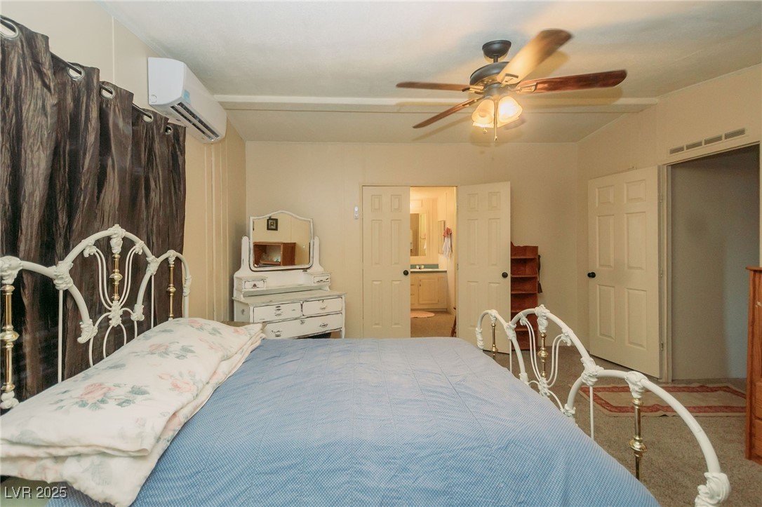 3485 Gally Road Pahrump, NV 89060 - Photo 67 of 90 Bedroom with a wall unit AC, a ceiling fan, carpet flooring, and ensuite bath