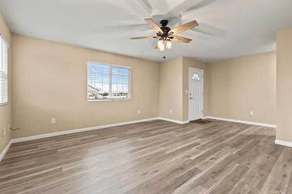 a view of an empty room with a window and wooden floor