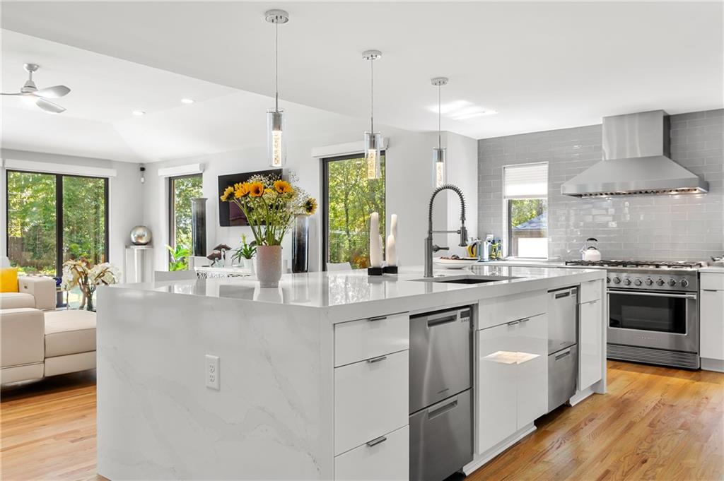 a large kitchen with stainless steel appliances a lot of white cabinets and wooden floors