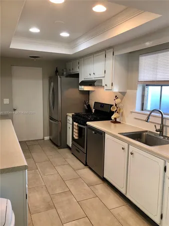 a kitchen with a sink a refrigerator and cabinets