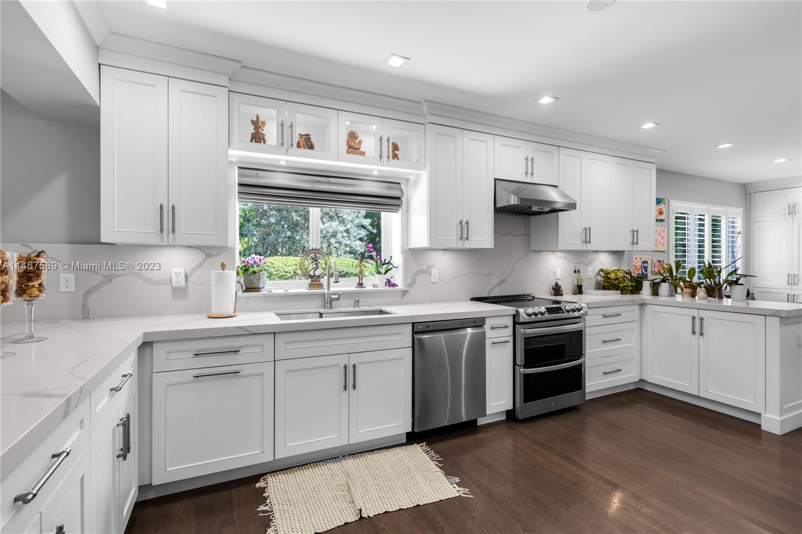 2400 Trapp Avenue Miami, FL 33133 - Photo 14 of 47 a large white kitchen with stainless steel appliances granite countertop a stove a sink dishwasher and white cabinets with wooden floor