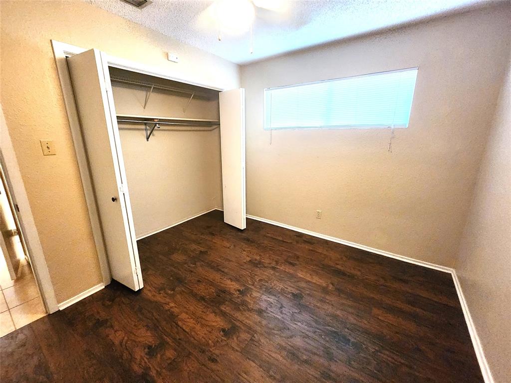610 Genard Street, Unit A Austin, TX 78751 - Photo 11 of 15 Unfurnished bedroom featuring a textured ceiling, a textured wall, dark wood-style flooring, a closet, and a ceiling fan
