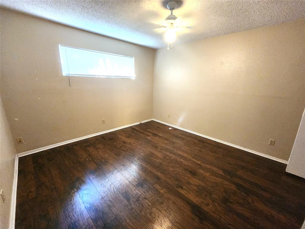 610 Genard Street, Unit A Austin, TX 78751 - Photo 12 of 15 Empty room featuring a textured ceiling, dark wood-type flooring, and a ceiling fan