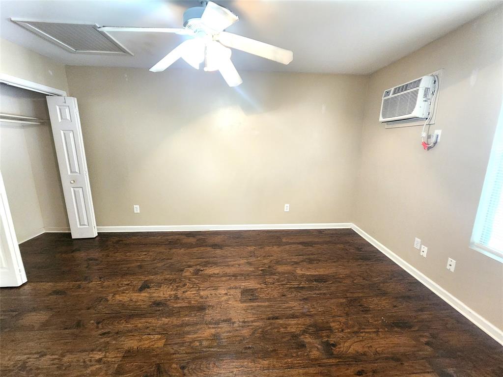 610 Genard Street, Unit A Austin, TX 78751 - Photo 14 of 15 Unfurnished bedroom featuring dark wood-type flooring, a ceiling fan, a closet, and a wall mounted AC