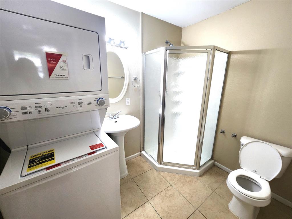 610 Genard Street, Unit A Austin, TX 78751 - Photo 6 of 15 Full bath with a stall shower, light tile patterned floors, and stacked washing machine and dryer