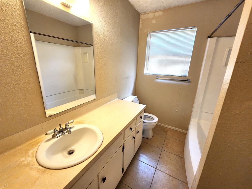 610 Genard Street, Unit A Austin, TX 78751 - Photo 7 of 15 Full bathroom featuring vanity, a textured wall, shower / tub combination, light tile patterned flooring, and a textured ceiling