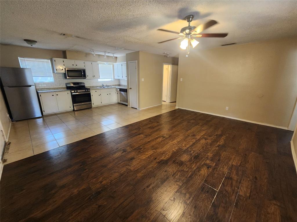 610 Genard Street, Unit A Austin, TX 78751 - Photo 8 of 15 Kitchen featuring stainless steel appliances, light wood-type flooring, white cabinetry, light countertops, and a textured ceiling