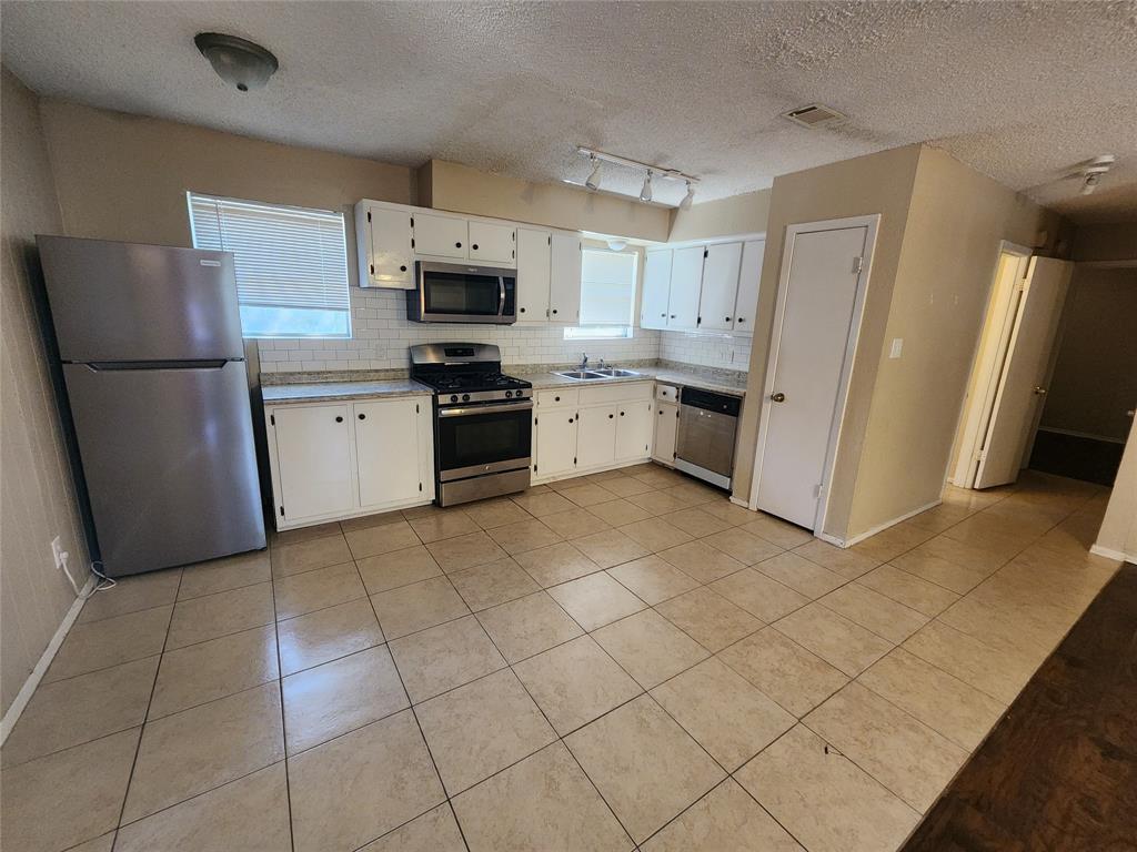 610 Genard Street, Unit A Austin, TX 78751 - Photo 9 of 15 Kitchen with stainless steel appliances, white cabinetry, light tile patterned floors, light countertops, and a textured ceiling