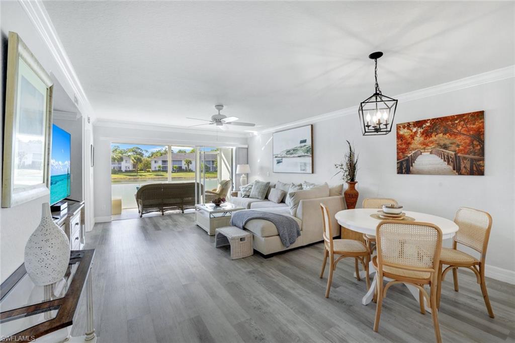 409 Gabriel Circle, Unit 2203 Naples, FL 34104 - Photo 11 of 24 Living room with crown molding, Coretex vinyl floors, ceiling fan, and water feature view.