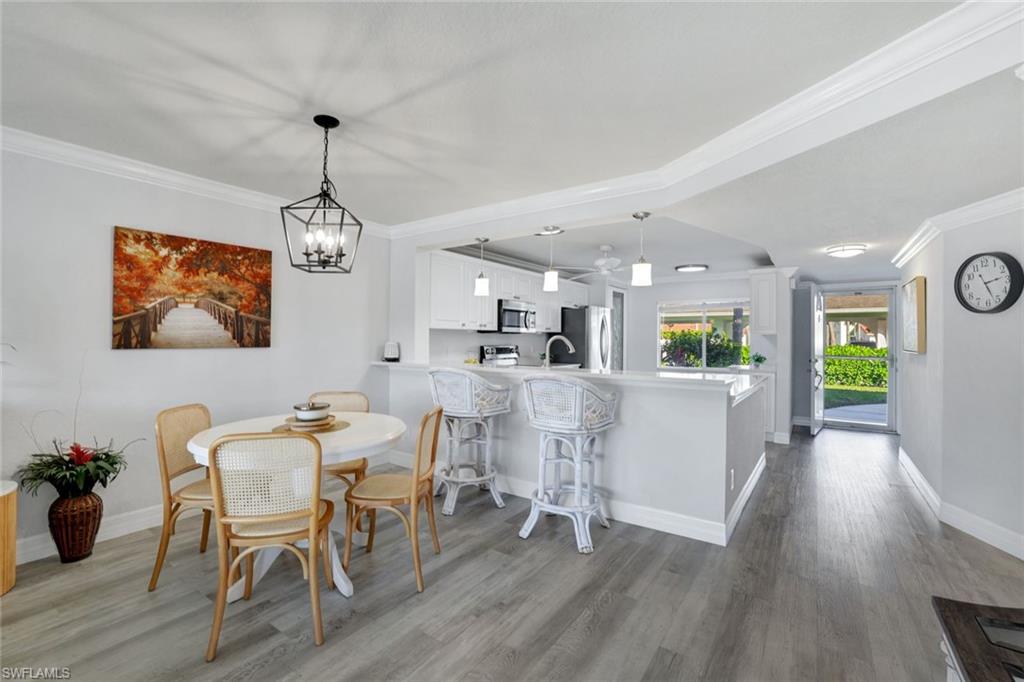 409 Gabriel Circle, Unit 2203 Naples, FL 34104 - Photo 13 of 24 Dining space featuring crown molding, lCoretex vinyl flooring, and light fixture.