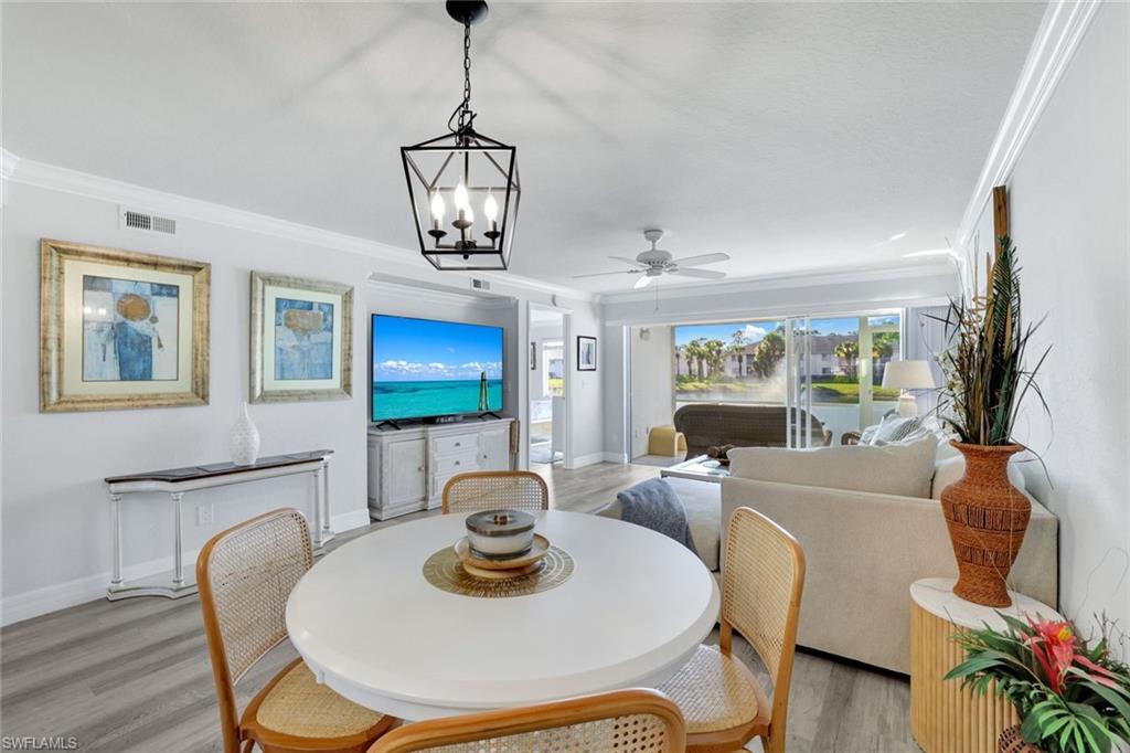 409 Gabriel Circle, Unit 2203 Naples, FL 34104 - Photo 14 of 24 Dining space featuring crown molding, lCoretex vinyl flooring, and light fixture.