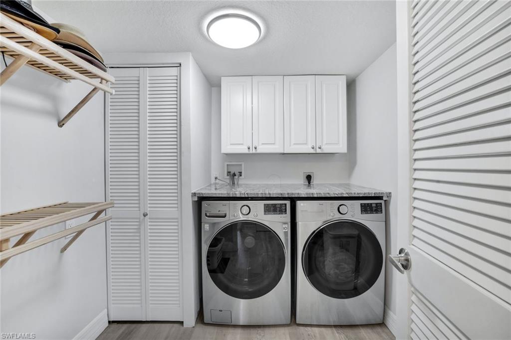 409 Gabriel Circle, Unit 2203 Naples, FL 34104 - Photo 17 of 24 Laundry room with cabinets, light hardwood / wood-style flooring, and washing machine and clothes dryer