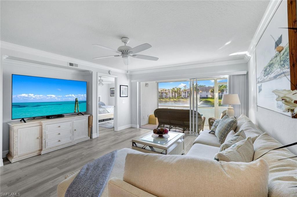 409 Gabriel Circle, Unit 2203 Naples, FL 34104 - Photo 2 of 24 Living room with crown molding, Coretex vinyl floors, ceiling fan, and water feature view.