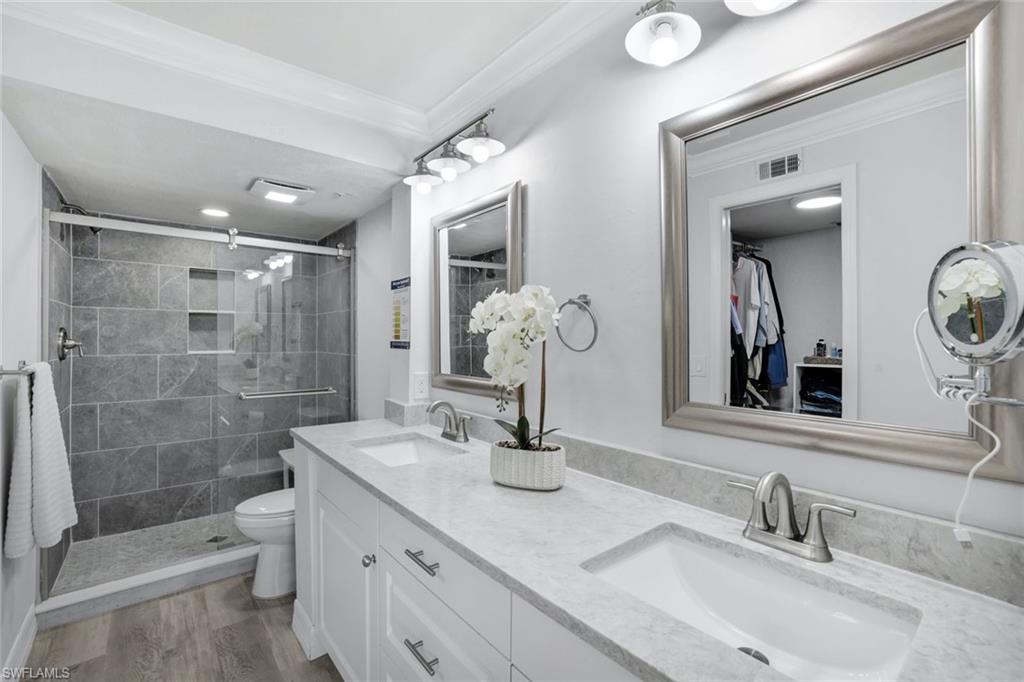 409 Gabriel Circle, Unit 2203 Naples, FL 34104 - Photo 4 of 24 Primary bathroom with vanity, toilet, crown molding, walk in shower, Coretex vinyl flooring