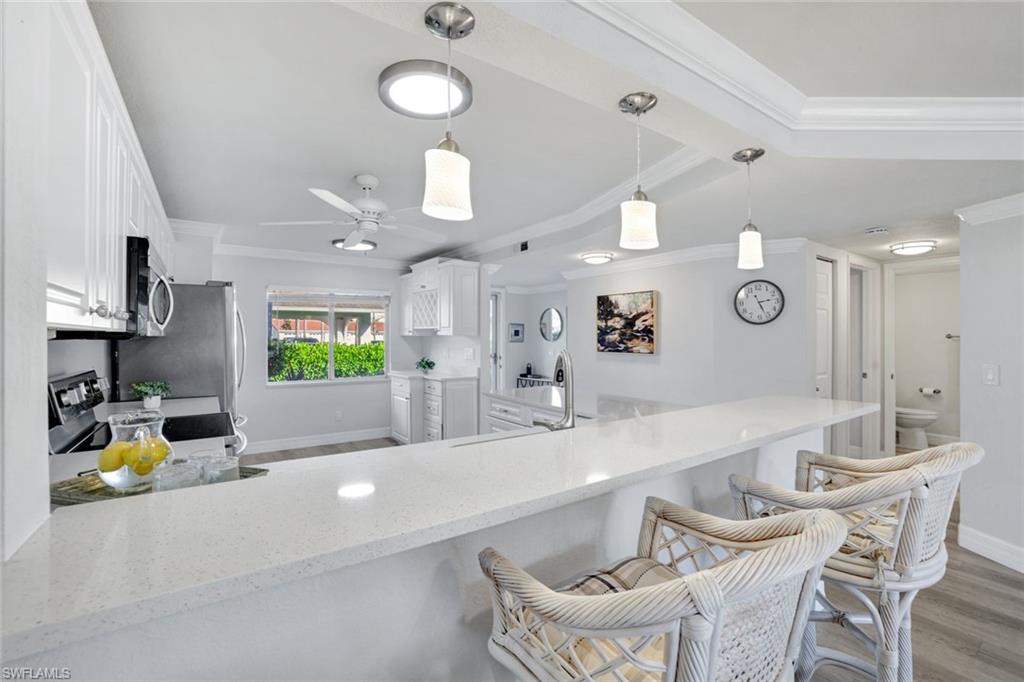 409 Gabriel Circle, Unit 2203 Naples, FL 34104 - Photo 10 of 24 Spacious kitchen featuring appliances with stainless steel finishes, Coretex vinyl flooring, decorative glass pantry door, and white cabinetry