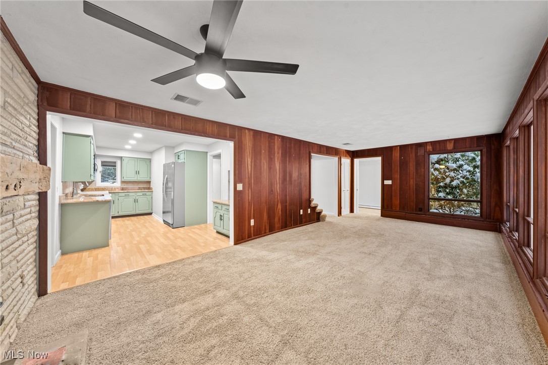 9513 Booth Road Willoughby, OH 44094 - Photo 18 of 45 Unfurnished living room with ceiling fan, crown molding, light carpet, and wooden walls