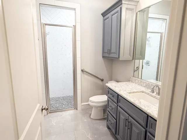 a bathroom with a granite countertop sink toilet and shower