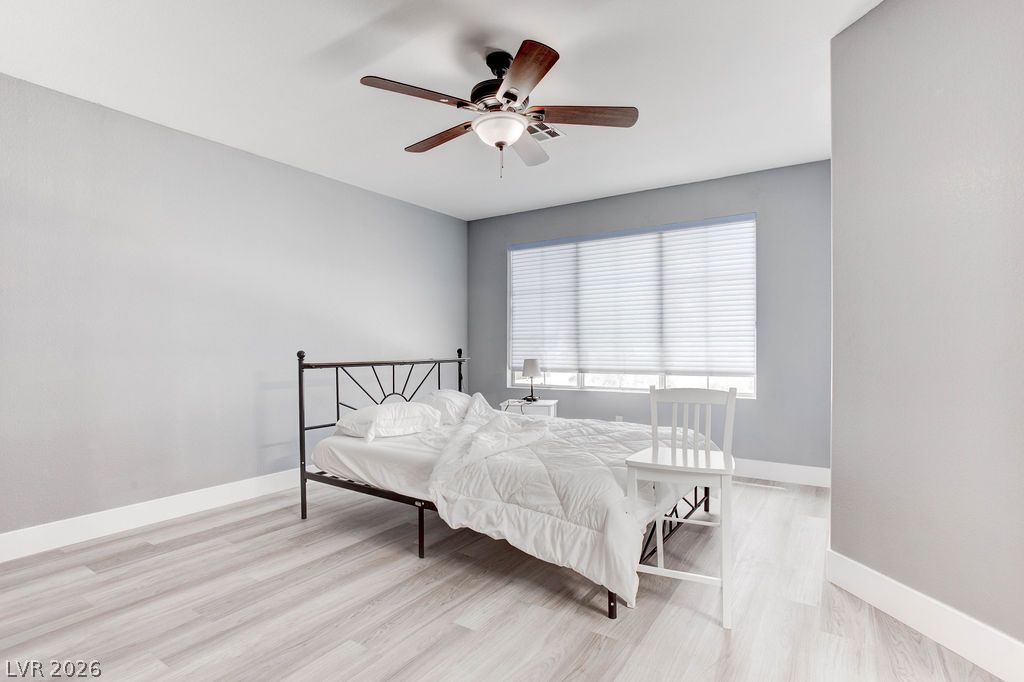 1 Rising Sun Court Henderson, NV 89074 - Photo 30 of 47 A well-lit bedroom features durable hardwood flooring and a functional ceiling fan for comfort.